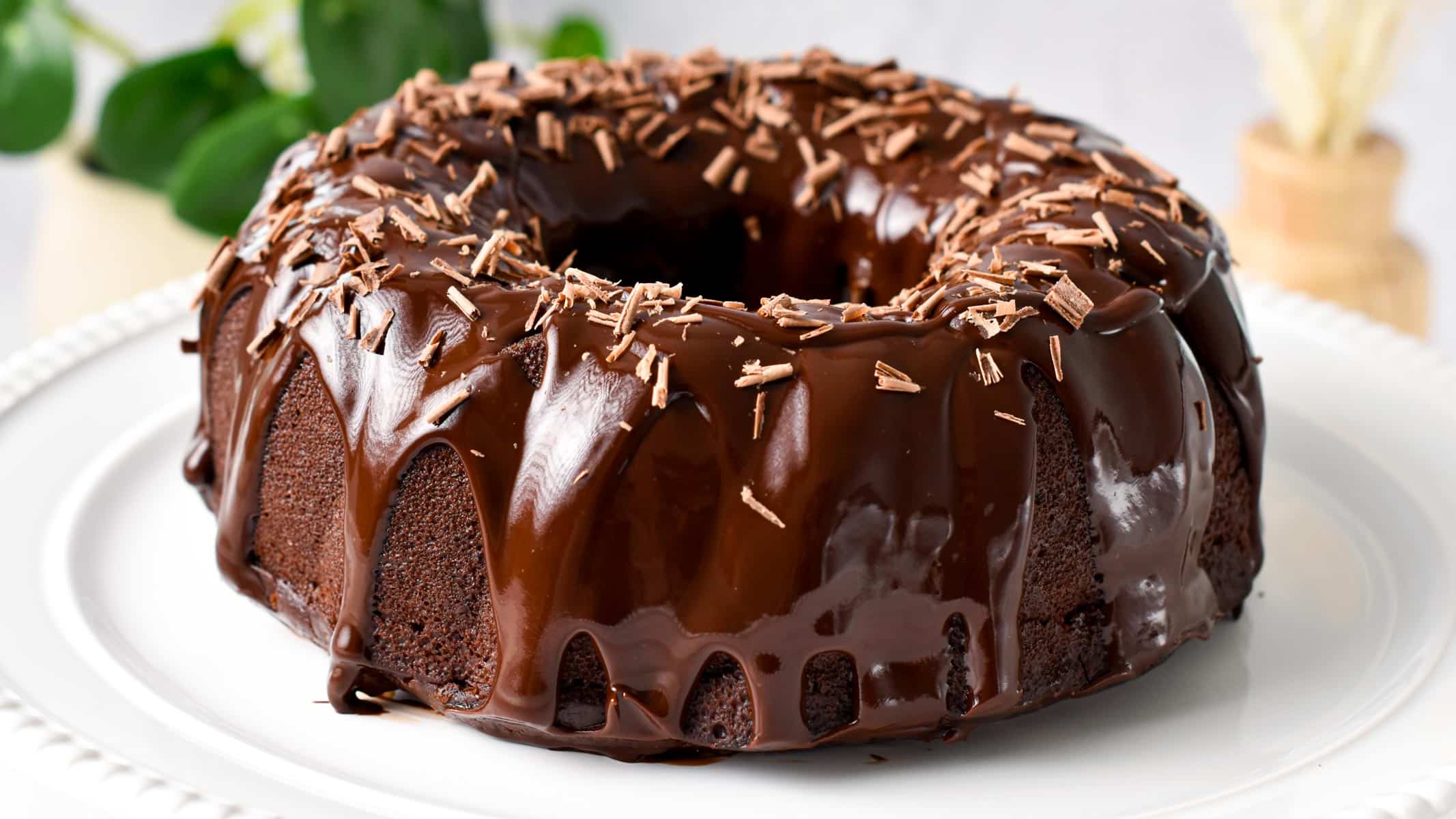 a chocolate Bundt Cake on a cake stand with drippy chocolate ganache