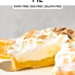 a vegan lemon meringue pie with golden-tipped blow torched meringue on top, and with lemon slices on sides