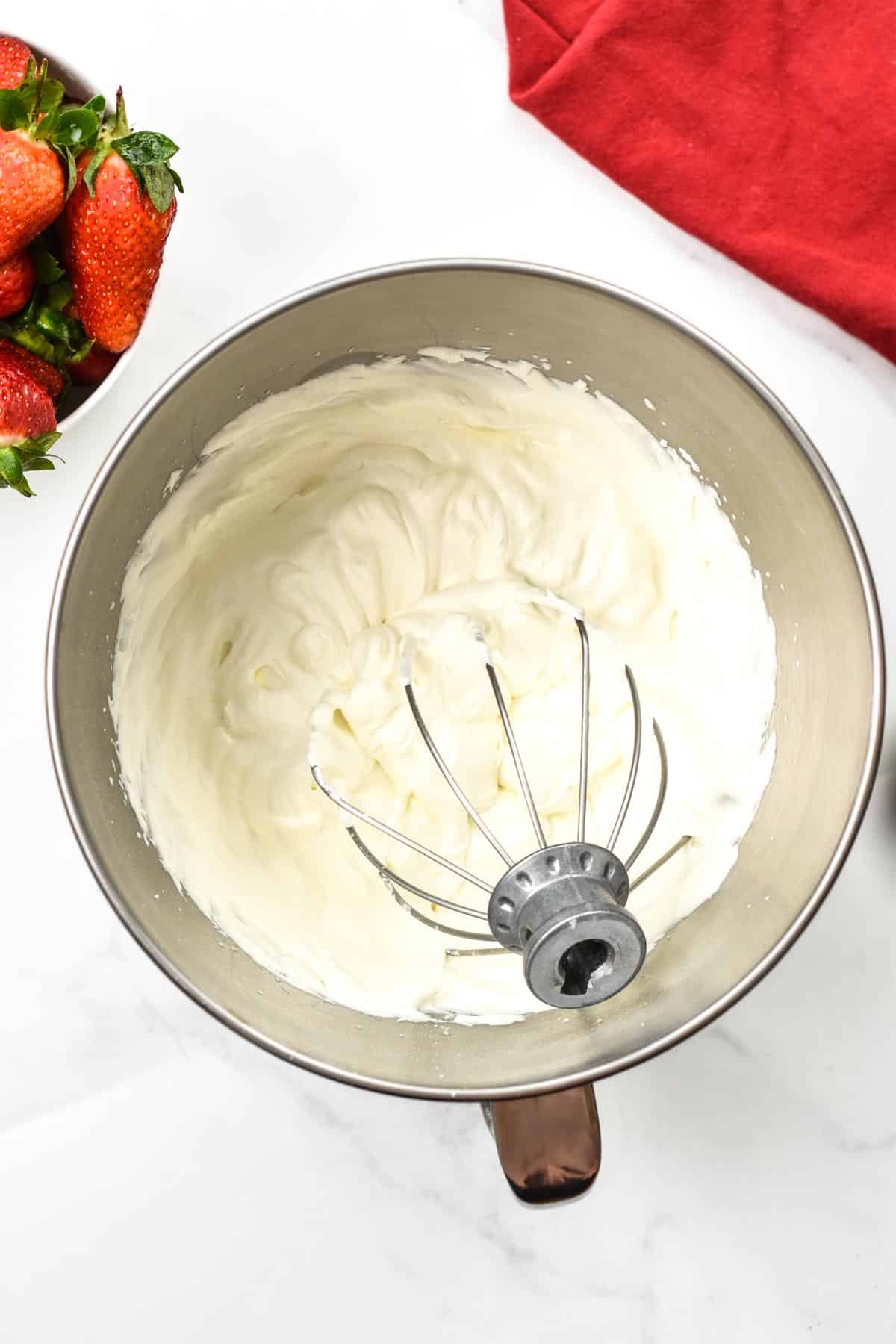 A bowl filled with homemade vegan whipped cream and a metallic whisk in the bowl.