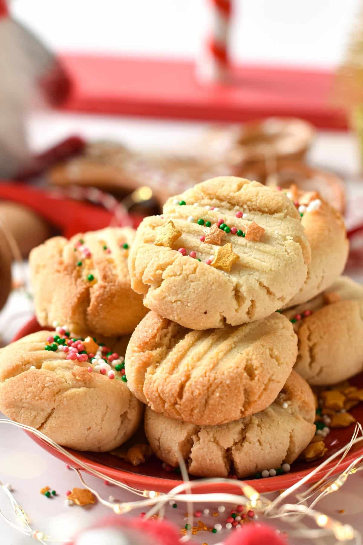 A stack of almond flour shortbread cookies with golden star sprinkles and red, green sprinkles pearls on top