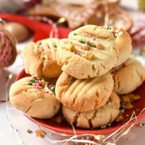 a stack of almond flour shortbread cookies with golden star sprinkles and red, green sprinkles pearls on top