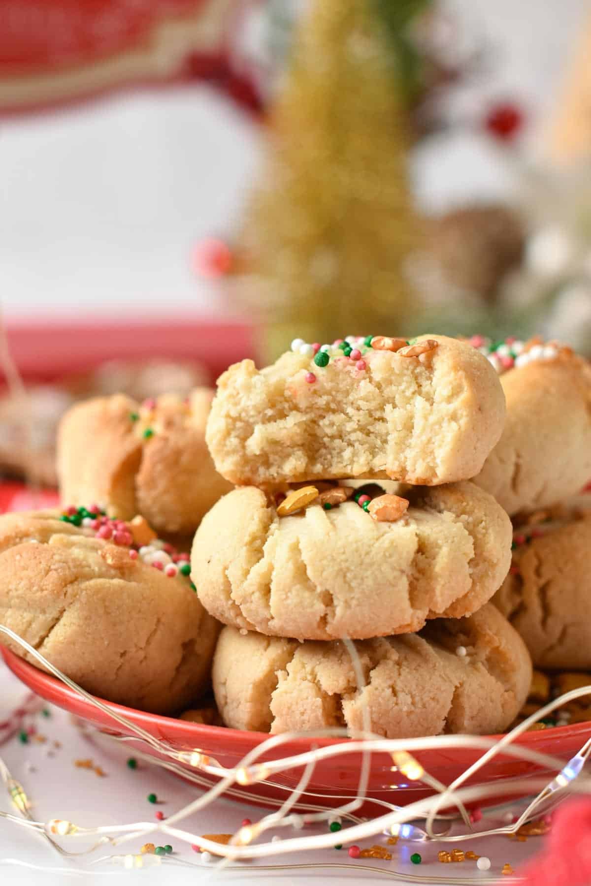 A stack of three almond flour shortbread cookies with the one on top half bitten.