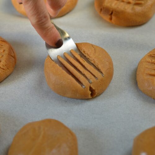 Healthy peanut butter cookies pressed with a fork on a baking tray.