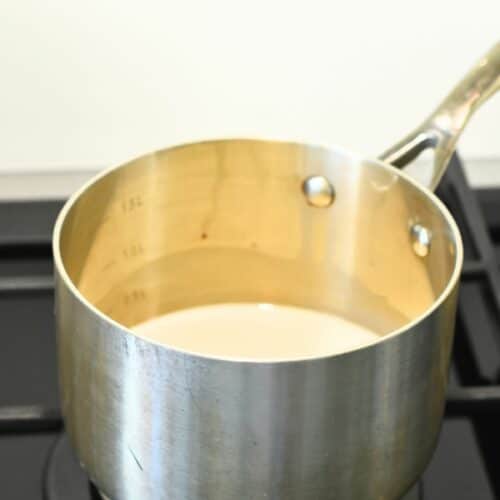 Heating almond milk in a saucepan on a stove.