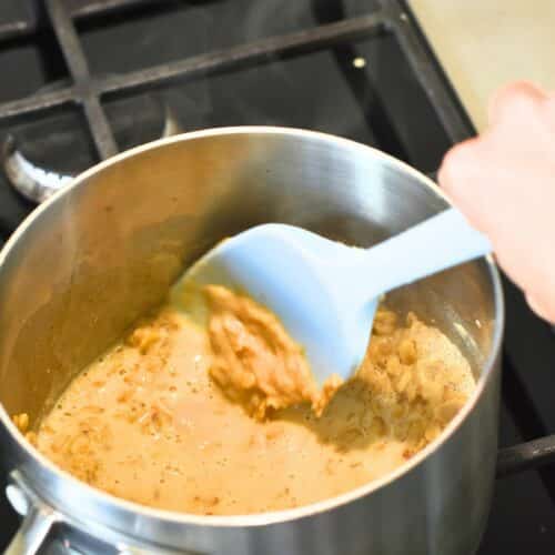 Stirring the protein oatmeal batter in a saucepan with a silicone spatula.