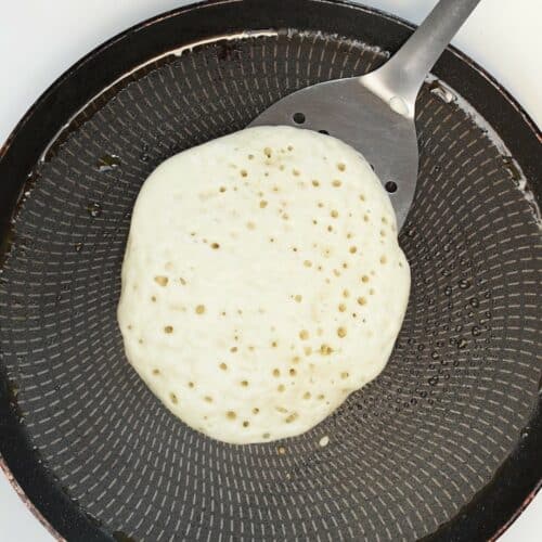 Vegan pancake of a crepe pan ready to be flipped.