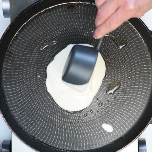 Pouring vegan pancake batter on a pan.