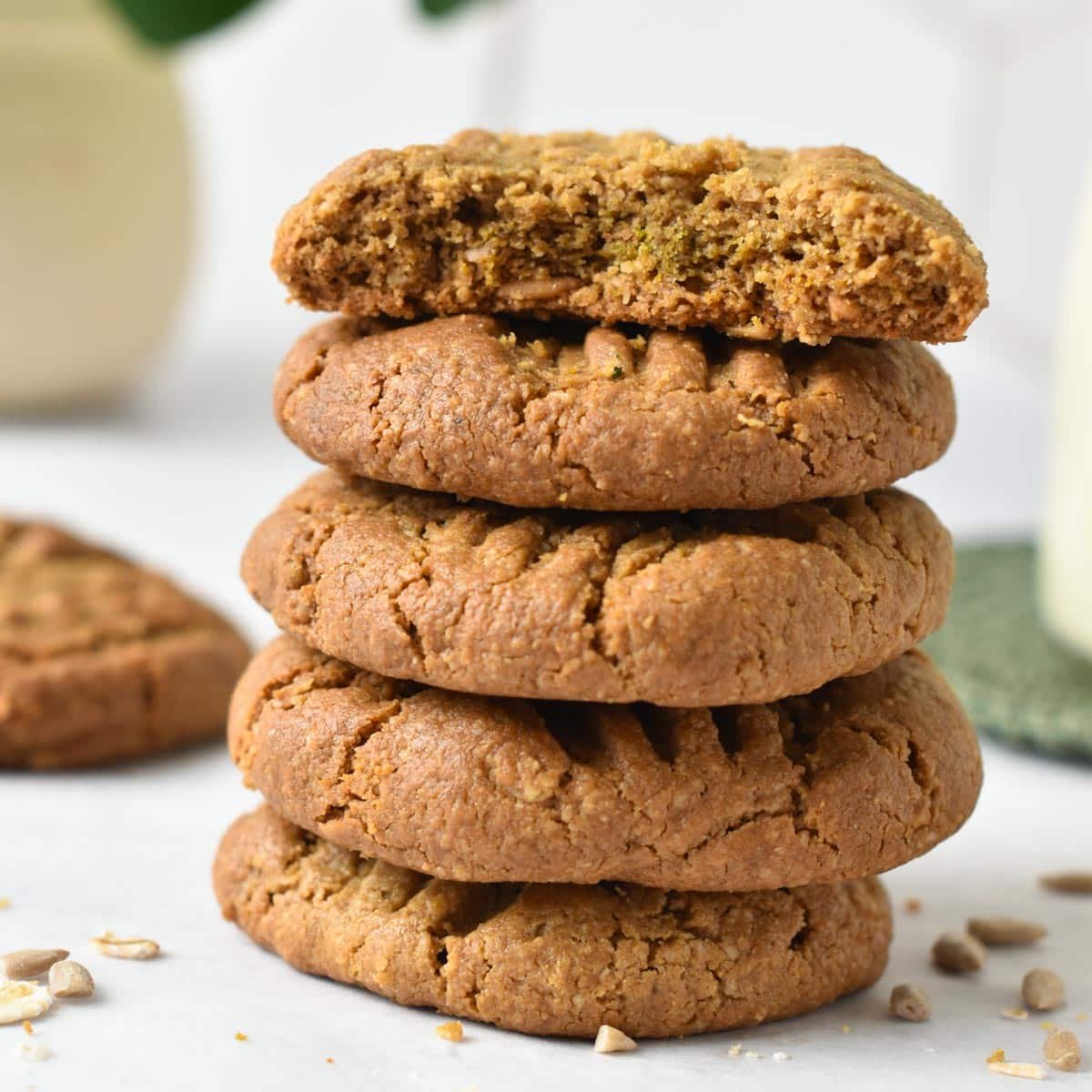 a stack of sunflower seed butter cookies with the one on top half broken showing the golden brown color