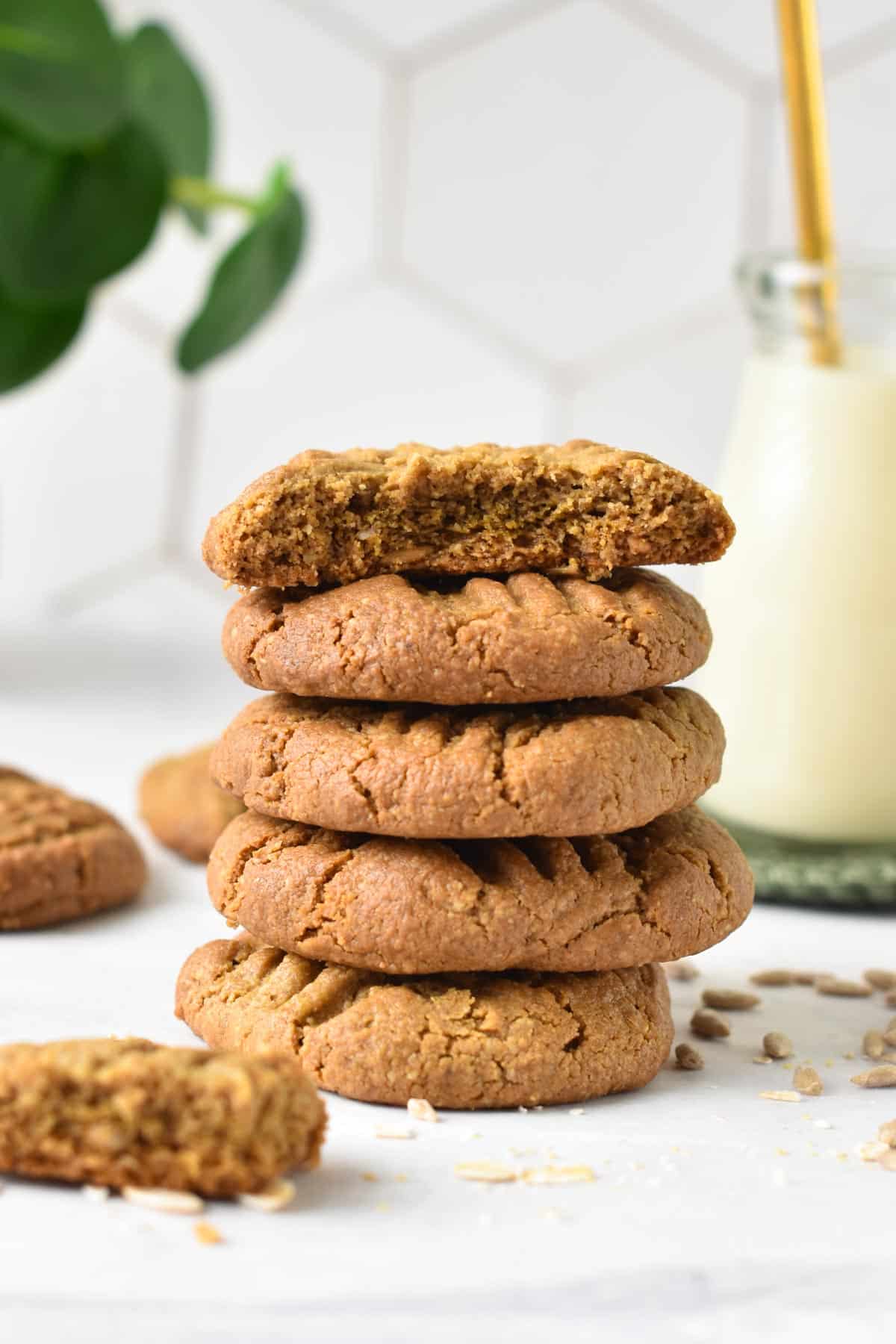 A stack of sunflower seed butter cookies with the one on top half broken showing the golden brown color.