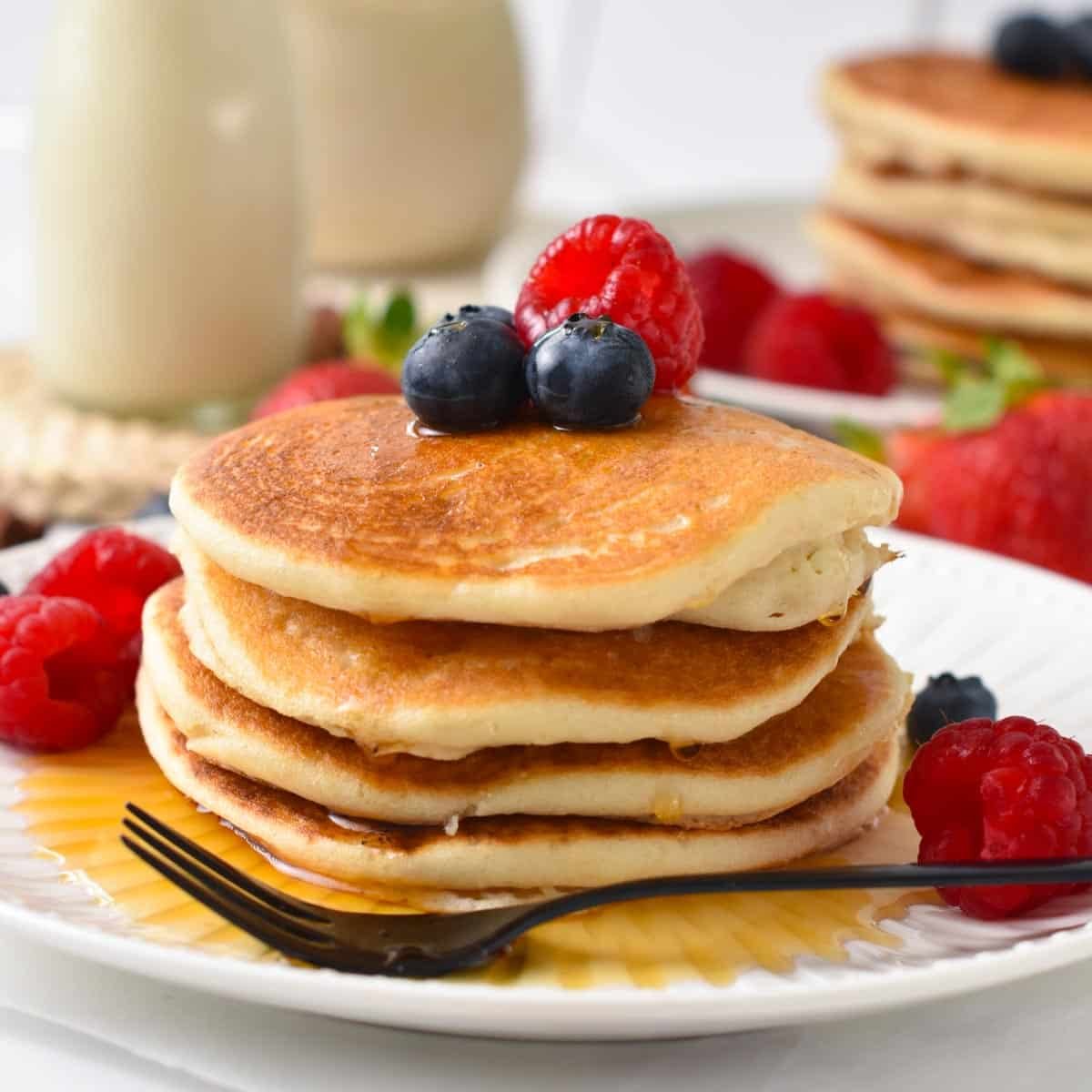 a stack of vegan almond flour pancakes with blueberries and raspberry on top