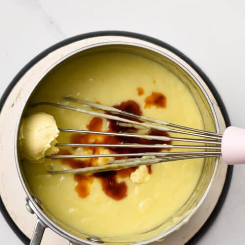 a whisk whisking in vegan butter and vanilla extract in creme brulee mixture