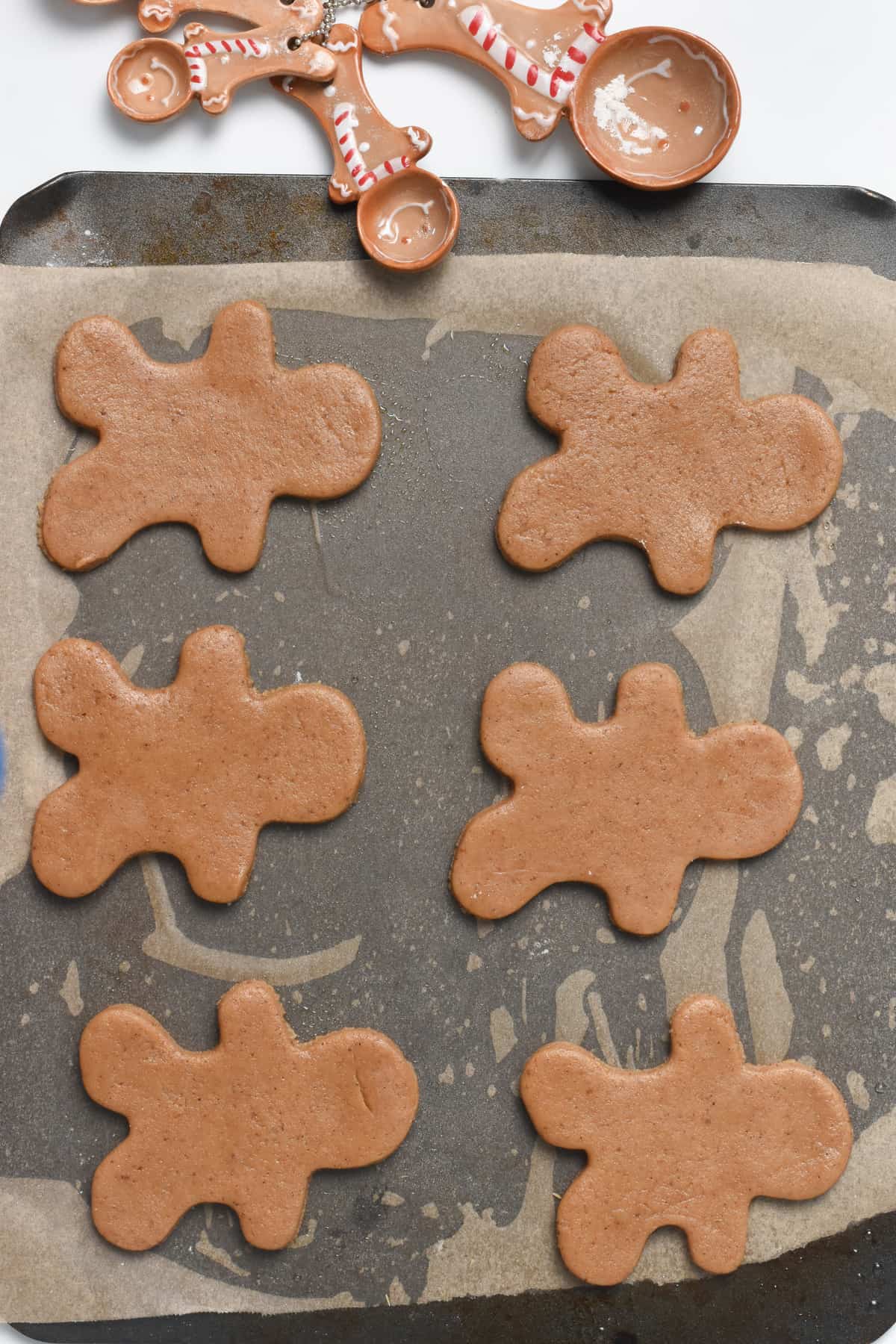 Vegan Gingerbread Cookies ready to bake on a large baking sheet with parchment paper.