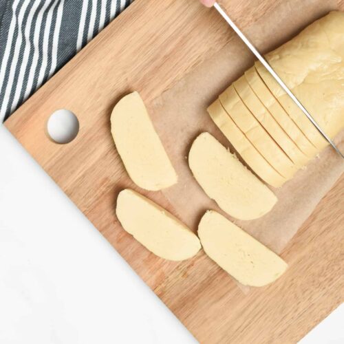 Cutting the vegan shortbread cookie log on a chopping board.