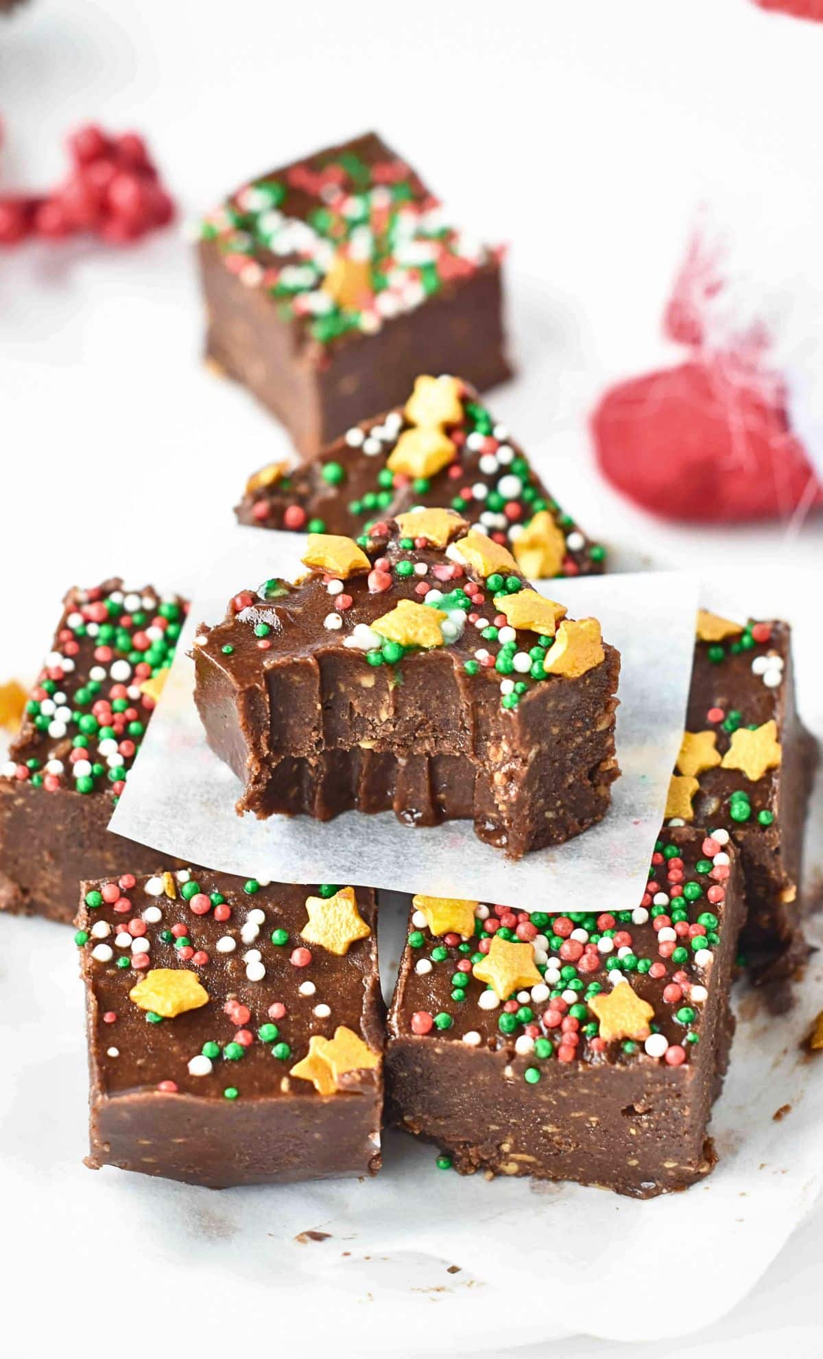4-Ingredient Chocolate Fudge stacked on a white table and decorated with golden sprinkles.