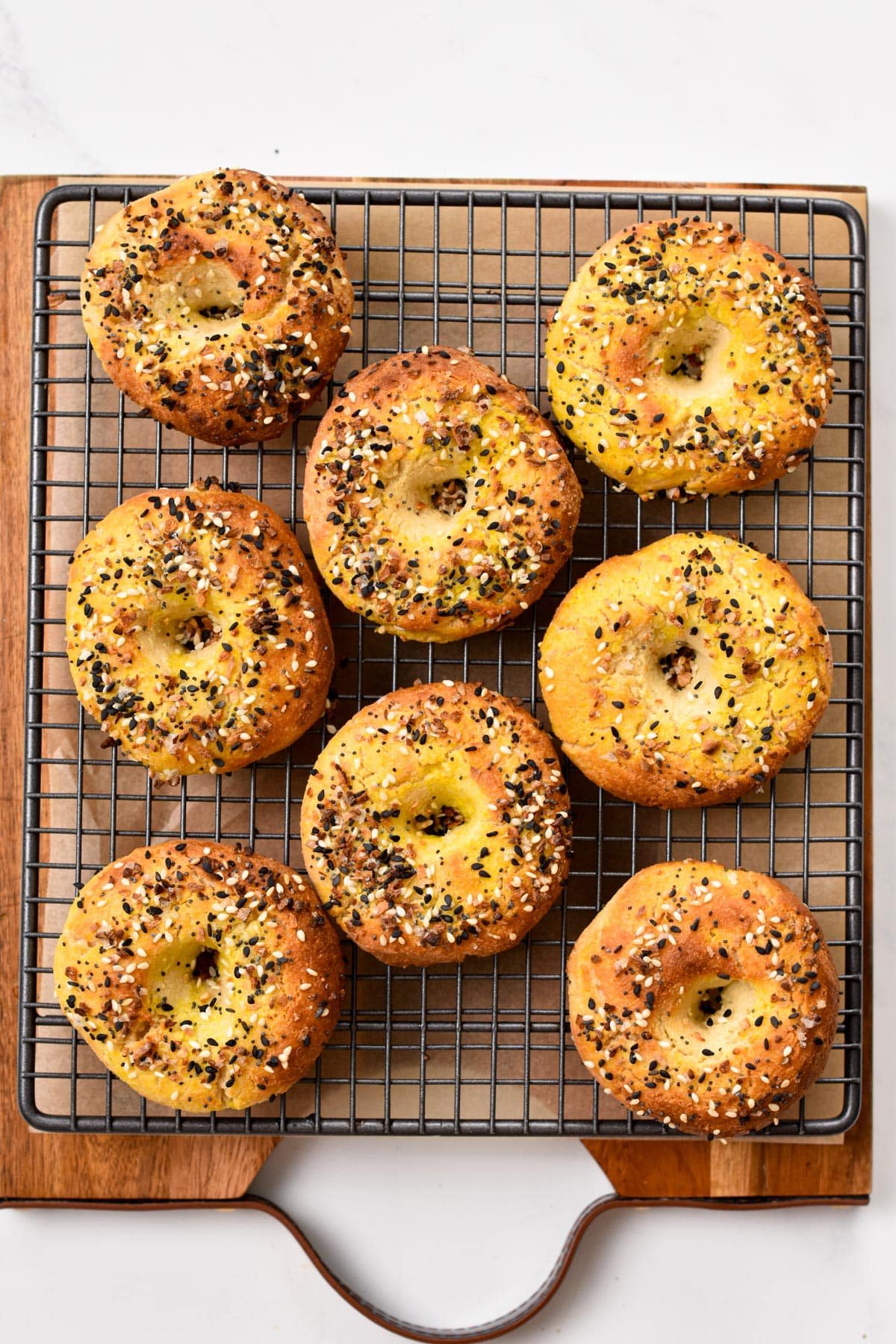 A picture from above with bagels on a cooling rack and topped with bagels seasonings