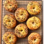 a picture from above with bagels on a cooling rack and topped with bagels seasonings