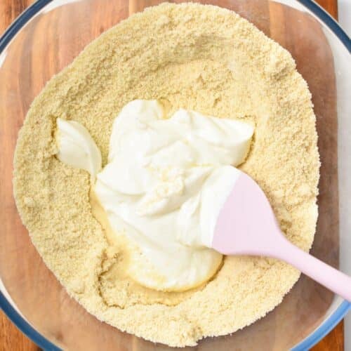 A bowl filled with almond flour, yogurt and a pink spatula.