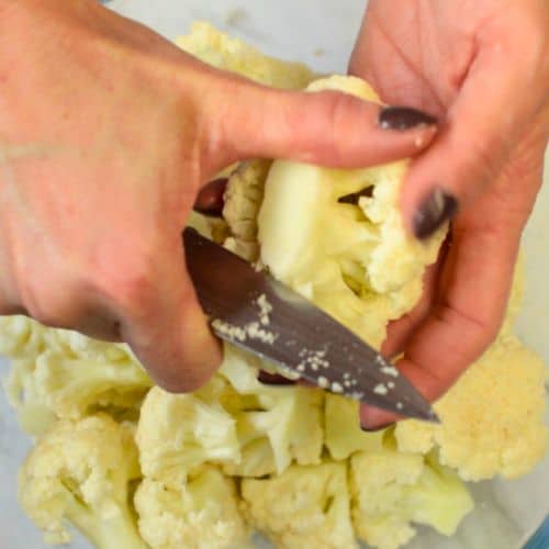 Cutting cauliflower into florets with a small knife.