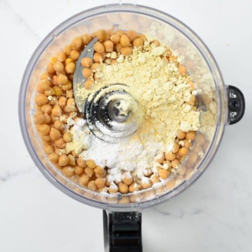 A food processor bowl filled with canned chickpeas, chickpea flour, tapioca flour.