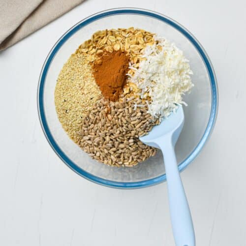 granola butter ingredients in a bowl with a silicone spatula.