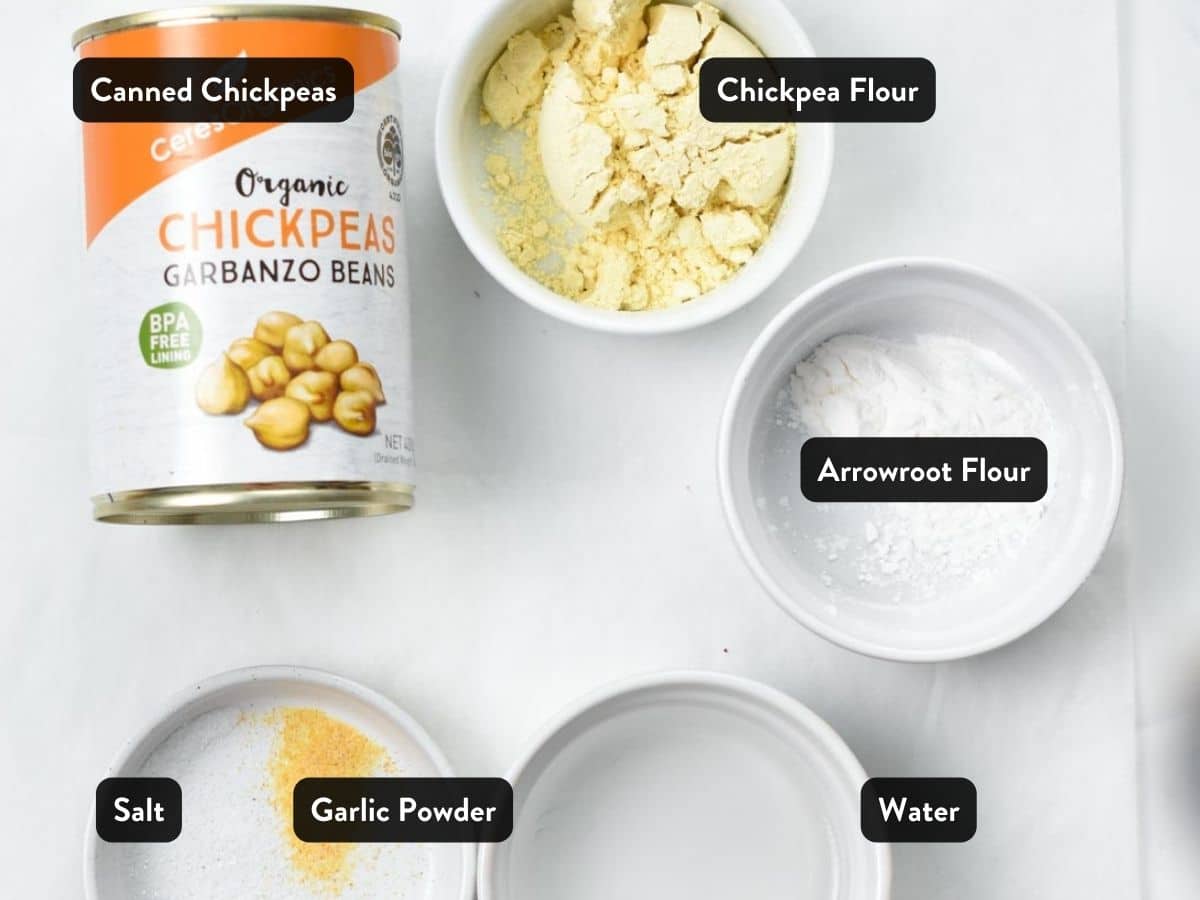 Ingredients used to make chickpea pizza crust: a can of chickpeas, chickpea flour, salt, garlic powder, water, and tapioca flour.