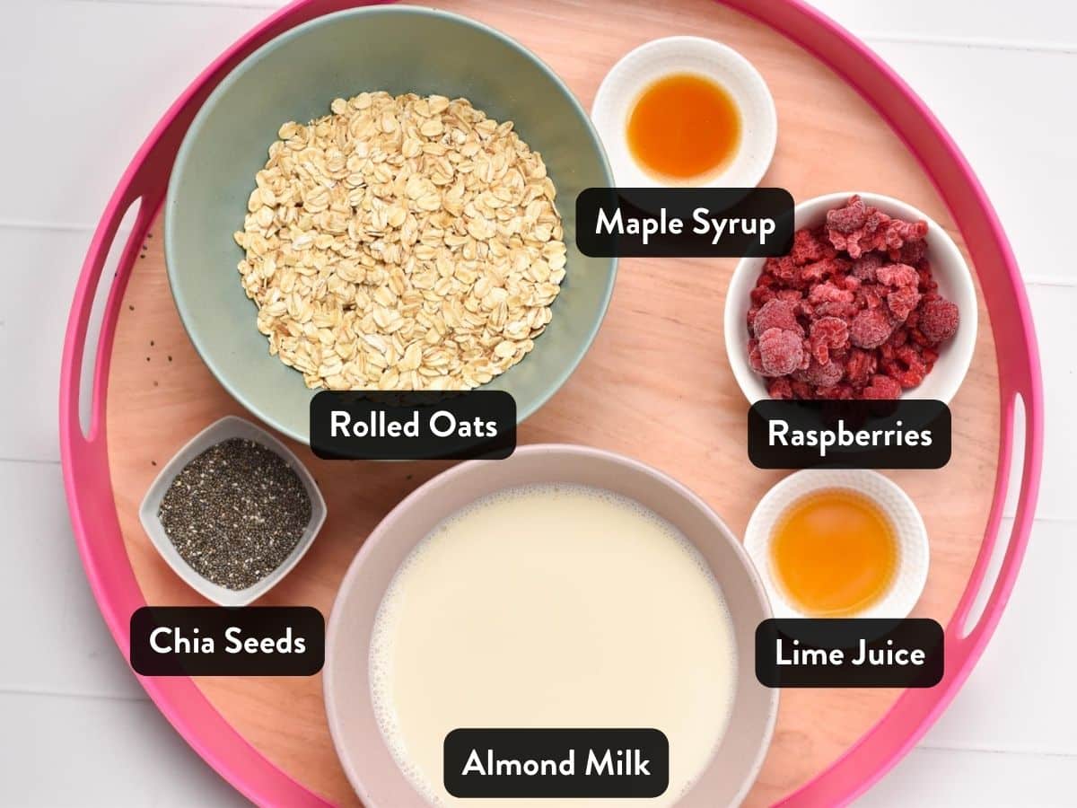 Ingredients for Raspberry Overnight Oats in various bowls and ramekins on a serving tray.