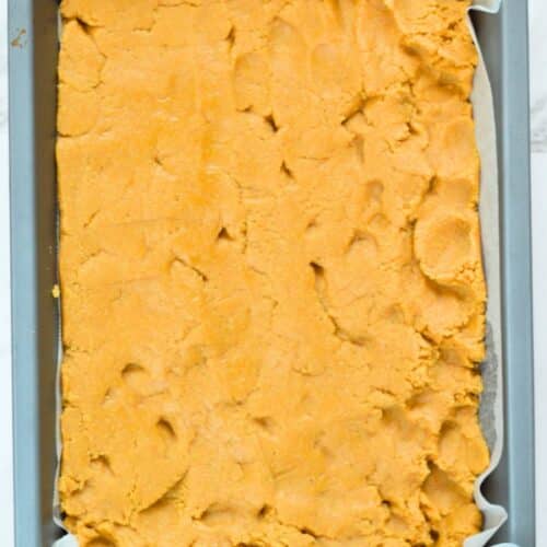 Peanut butter base layer pressed on a baking sheet.