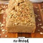 a oat flour bread loaf with toasted oats on top and a golden knife on side