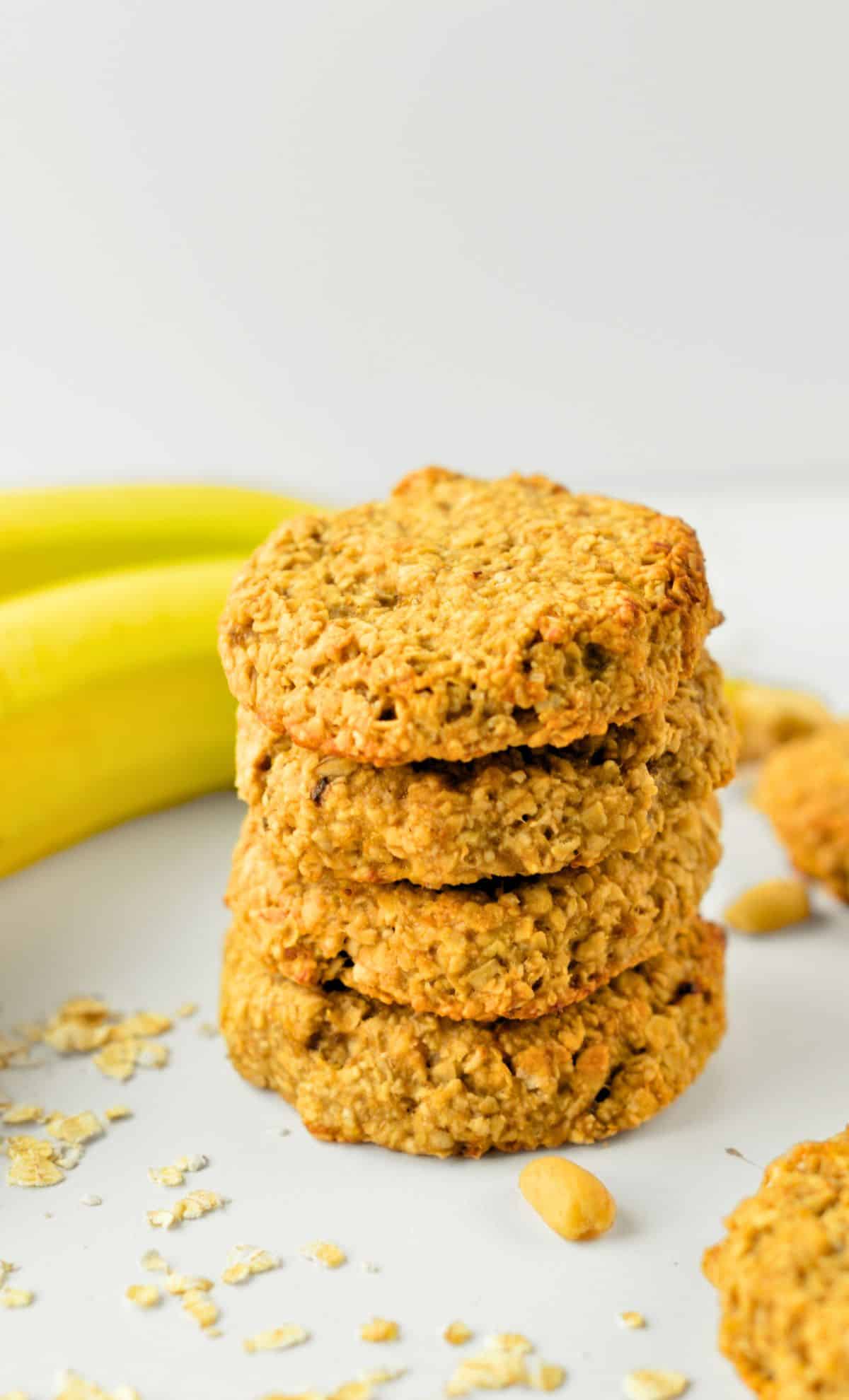 Peanut Butter Banana Oatmeal Cookies stacked in front of fresh banans