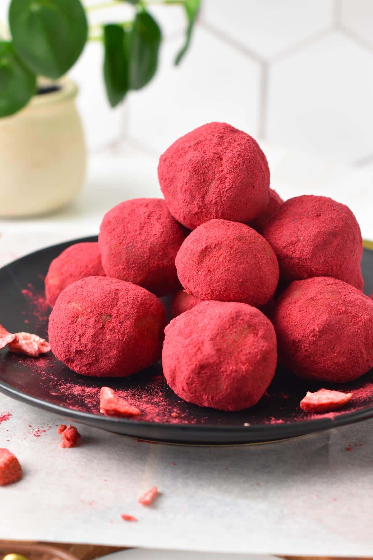 A black plate filled with a stack of pink Strawberry Protein Balls