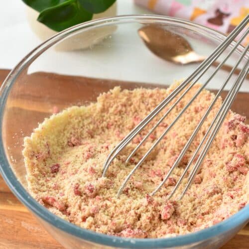 a bowl filled with dry ingredients to make strawberry protein balls and a whisk in the bowl