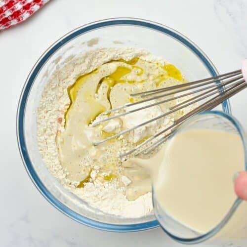 Pouring soy milk on the dry crepe ingredients in a large mixing bowl.