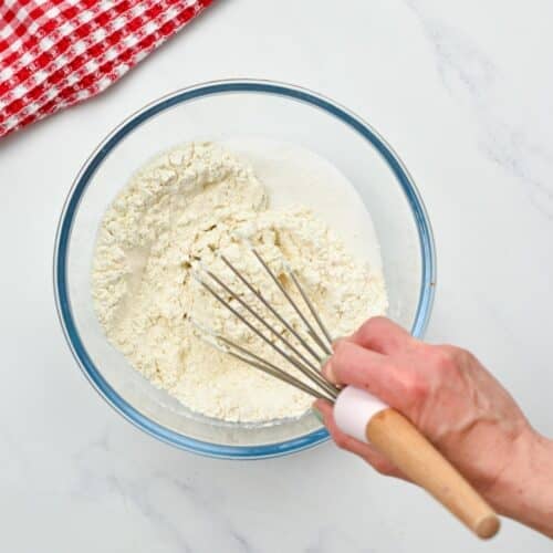 Combining dry ingredients for the vegan crepes in a bowl with a whisk.