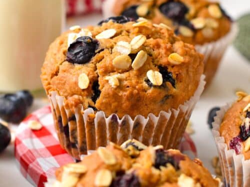 a vegan oatmeal muffin with blueberries,oats on top and placed on red and white round lid