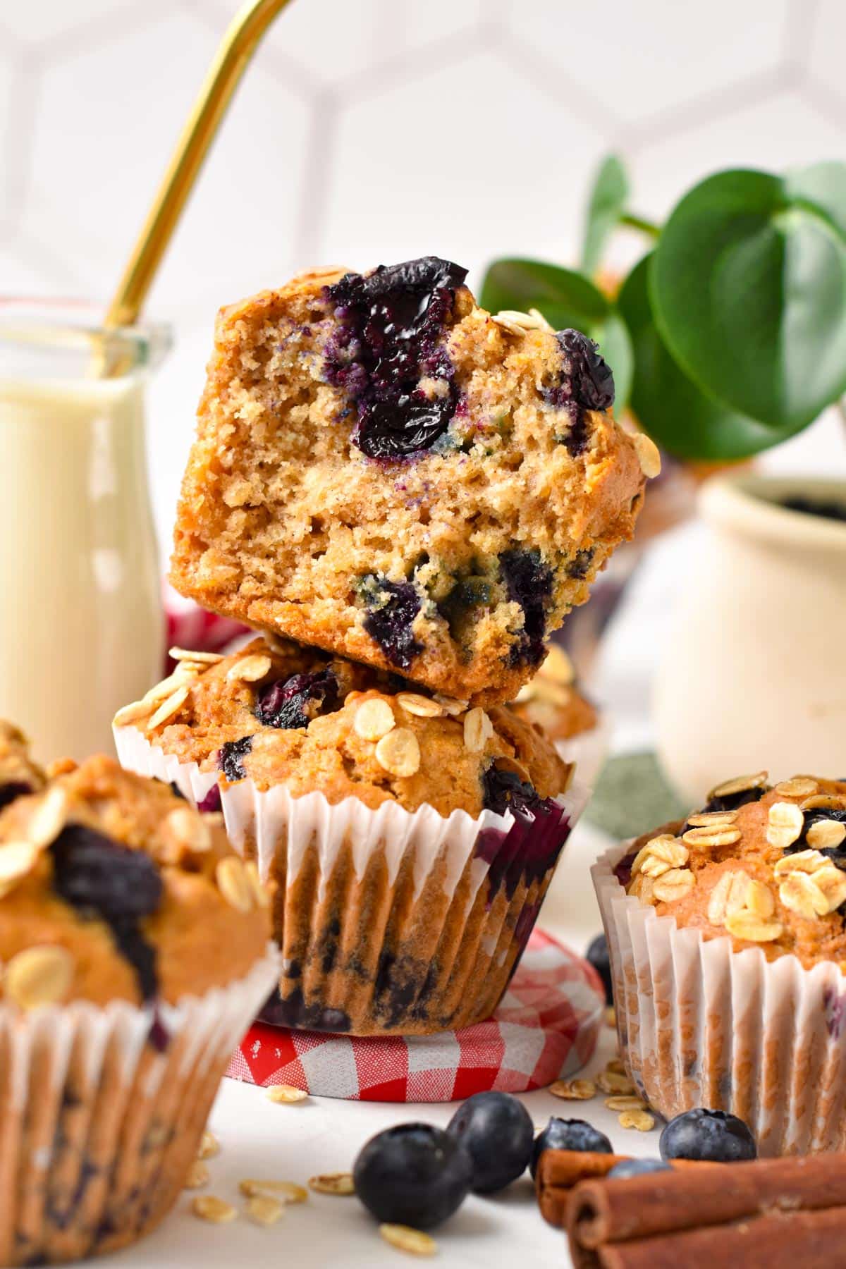 A stack of two vegan blueberry oatmeal muffins with the one on top half eaten showing the inside fluffy texture.