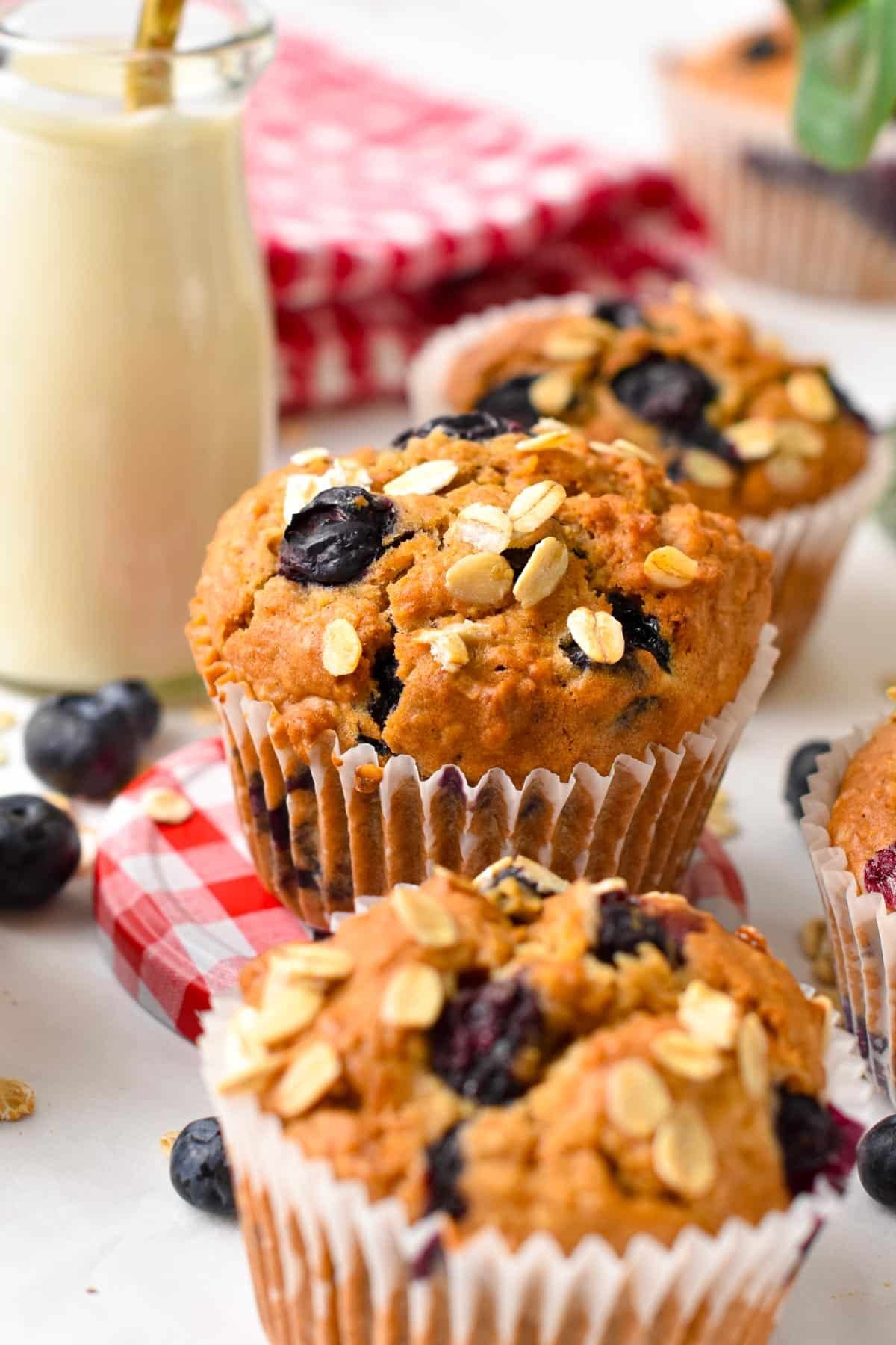 Vegan oatmeal muffins with blueberries and oats on top and placed on red and white round lid.