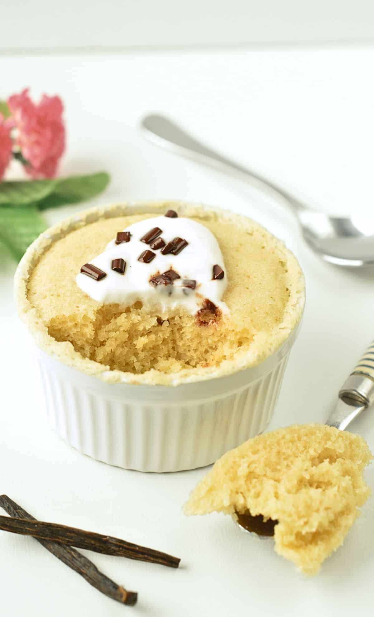 Vegan Vanilla Mug Cake is a small ramekin decorated with coconut yogurt and chocolate chips.
