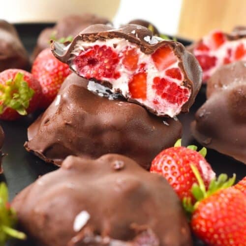 a stack of strawberry raspberry yogurt clusters coated with dark chocolate with the top cluster half open showing the texture inside