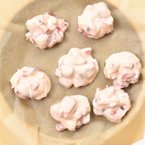 a plate covered with parchment paper and frozen yogurt clusters on top 