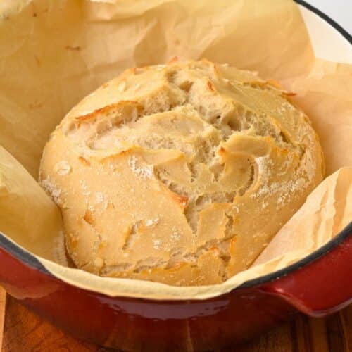 a 2 ingredient bread half baked in red dutch oven pan