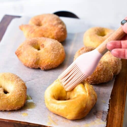 a pink silicone pastry brush brushing an air frier donuts with melted plant-based butter