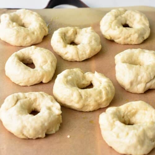 Aight donuts on a baking sheet with parchment paper before being air fried.