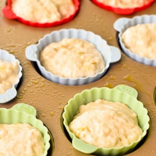 silicone muffins cups in a baking tray filled with banana muffin batter