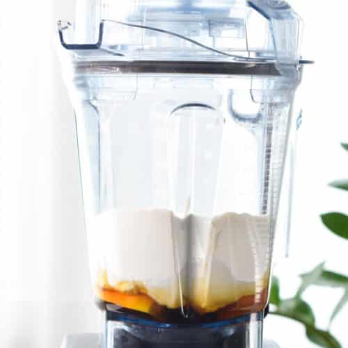 a blender jug filled with lemon, maple syrup, yogurt and flour 