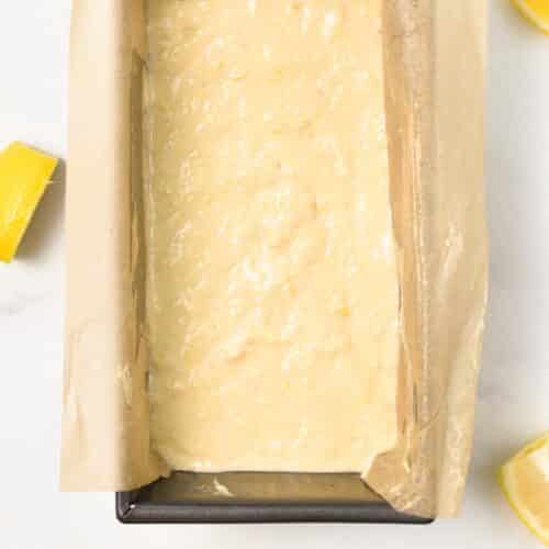 a lined loaf pan with parchment paper and filled with unbaked lemon cake batter