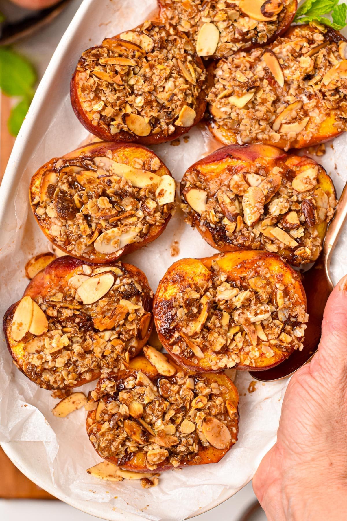 A serving dish with lots of air fried peach halves topped with crispy oat crumble.