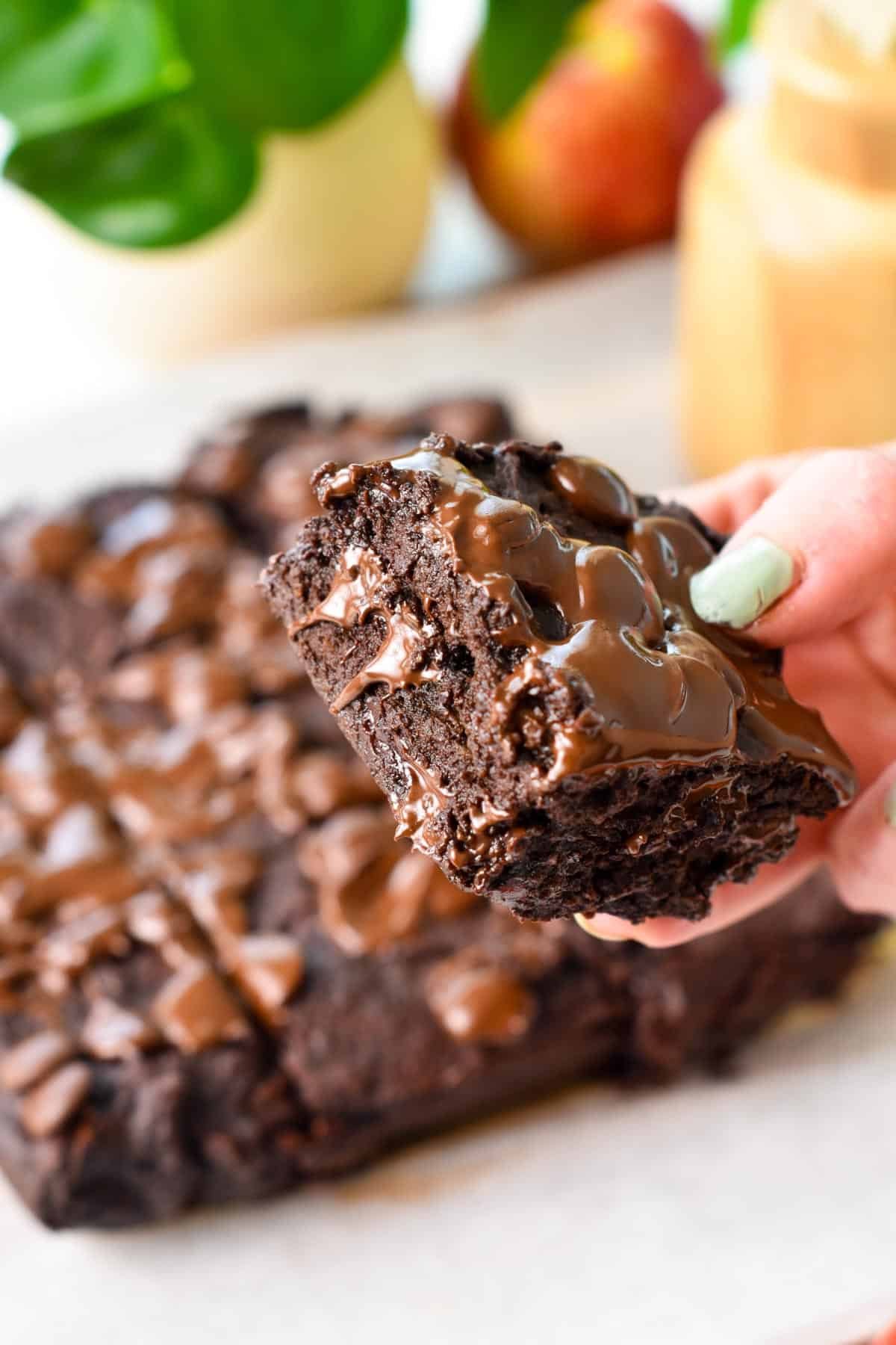 a hand holding a piece of ultra fudgy applesauce brownies
