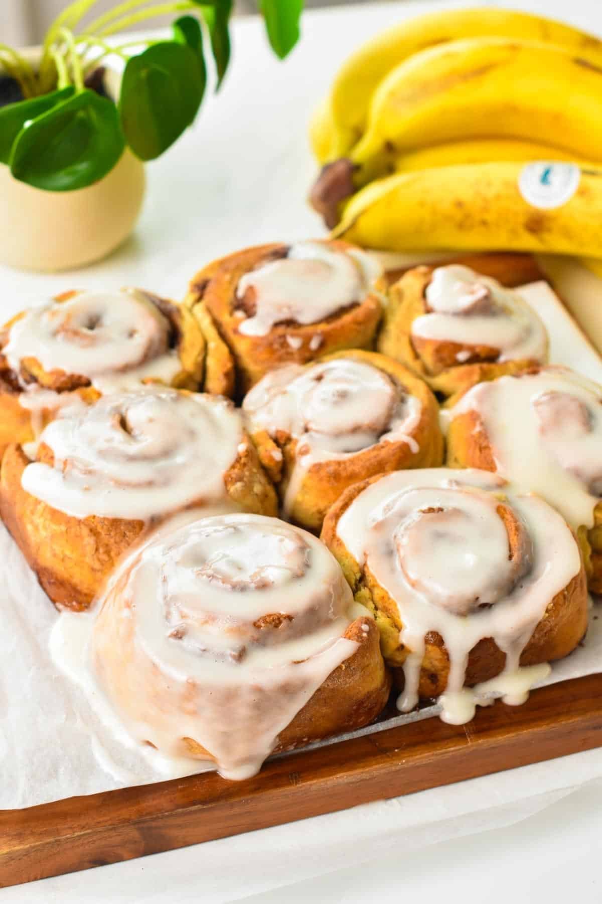 A batch of baked banana cinnamon rolls with glaze.