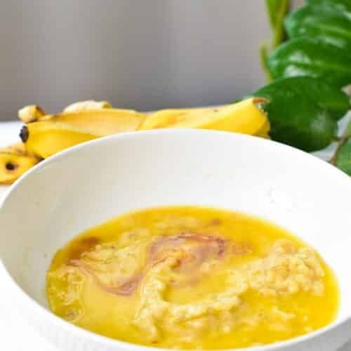 a bowl filled with mashed banana, vanilla extract, and melted butter