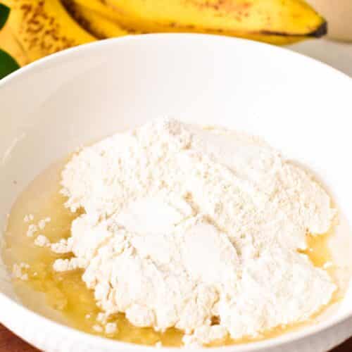 a bowl with flour, melted coconut oil, and mashed banana